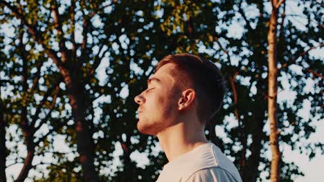 side profile of a man basking in sunlight amidst trees, captured with a low-angle shot