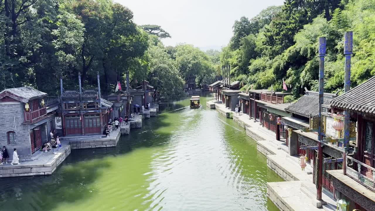 A traditional Chinese boat sails gracefully through the historic cultural town of the Summer Palace in Beijing.