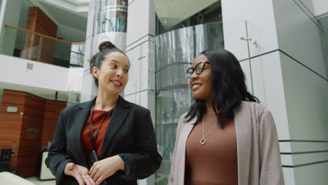 multiethnic businesswomen walking in office center and talking