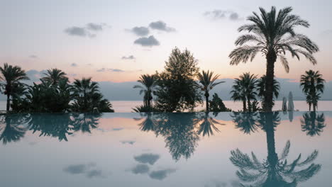 Serena-Escena-De-Resort-Al-Atardecer,-Piscina-Y-Mar-Con-Montañas.