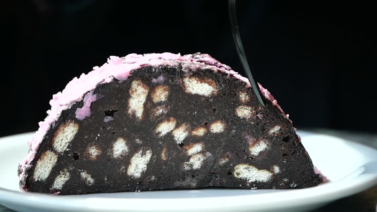 분홍색 토핑으로 초콜릿 케이크 한 조각을 먹는 사람.