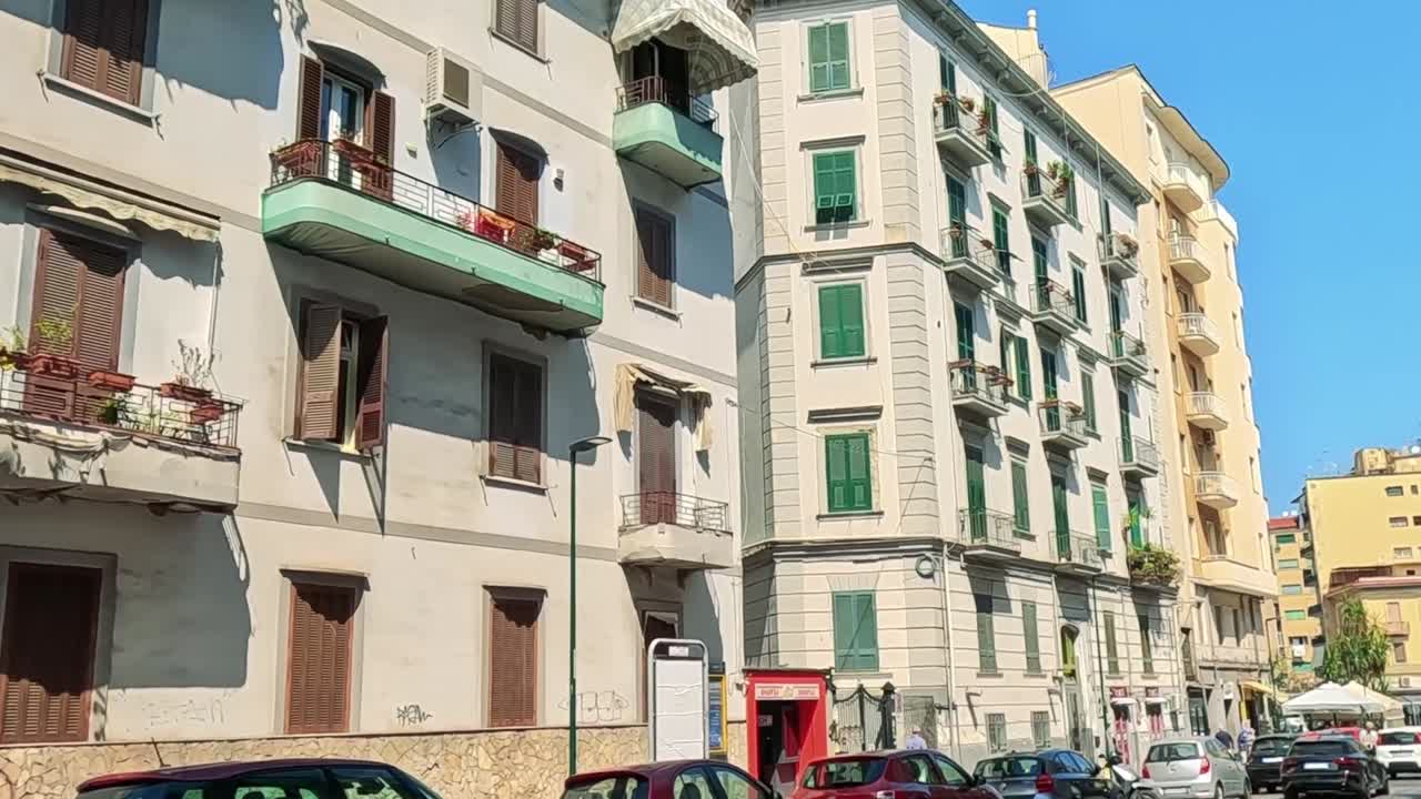Una vista dal basso di palazzi residenziali mediterranei a più piani sotto un cielo azzurro e limpido.