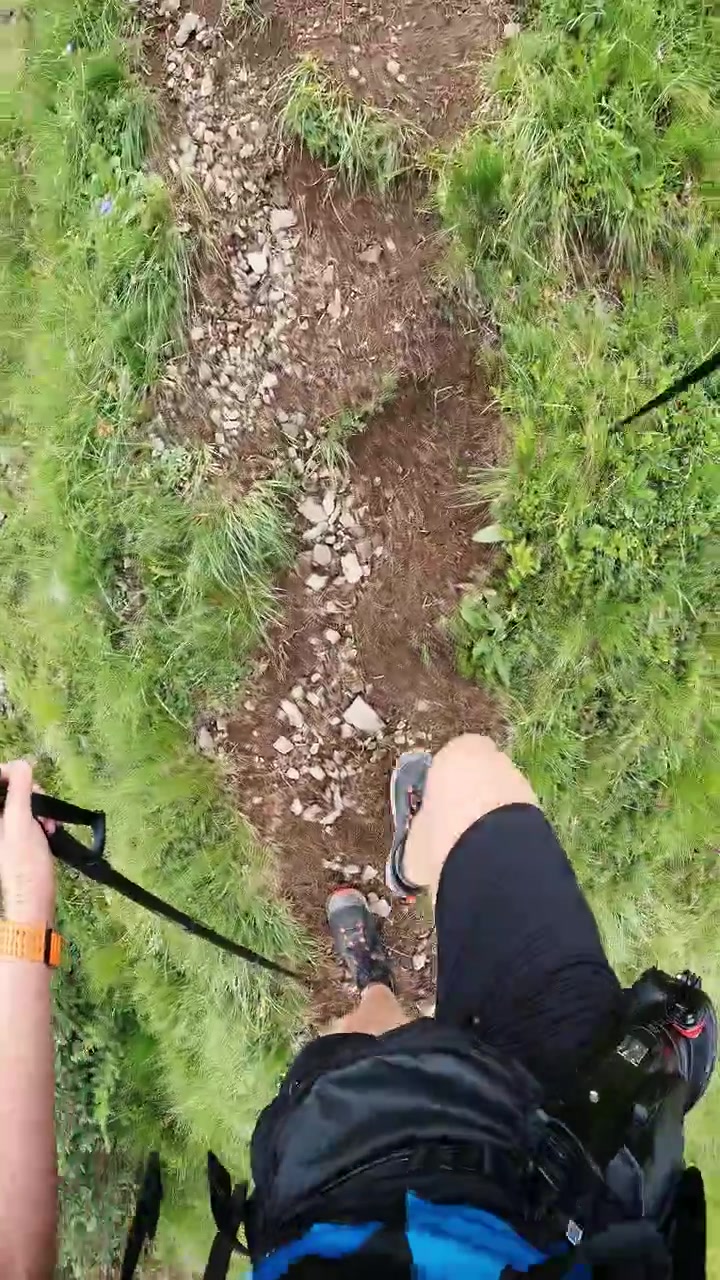 POV: Mann steigt steilen alpinen Wanderweg mit Trekkingstöcken nahe Col de la Puina hinauf.