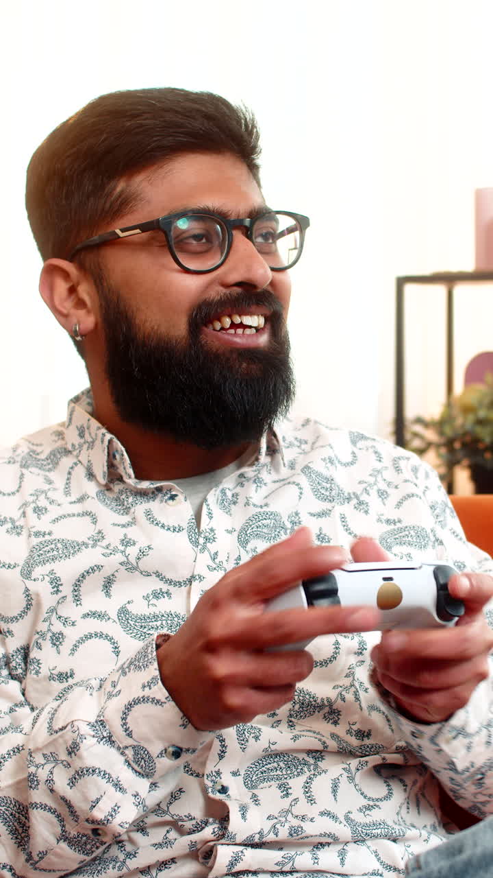 Indian man playing video game with joystick controller while at home focused and excited mood