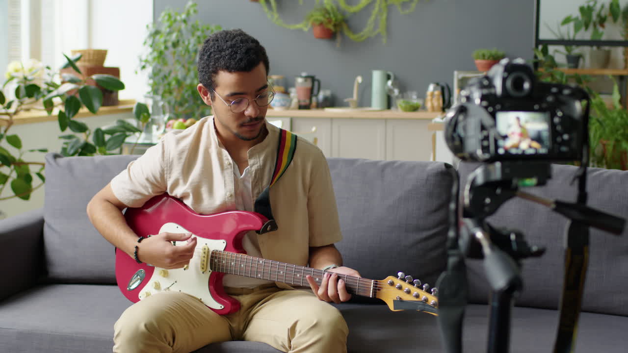 Man Playing Guitar and Filming Music Blog at Home