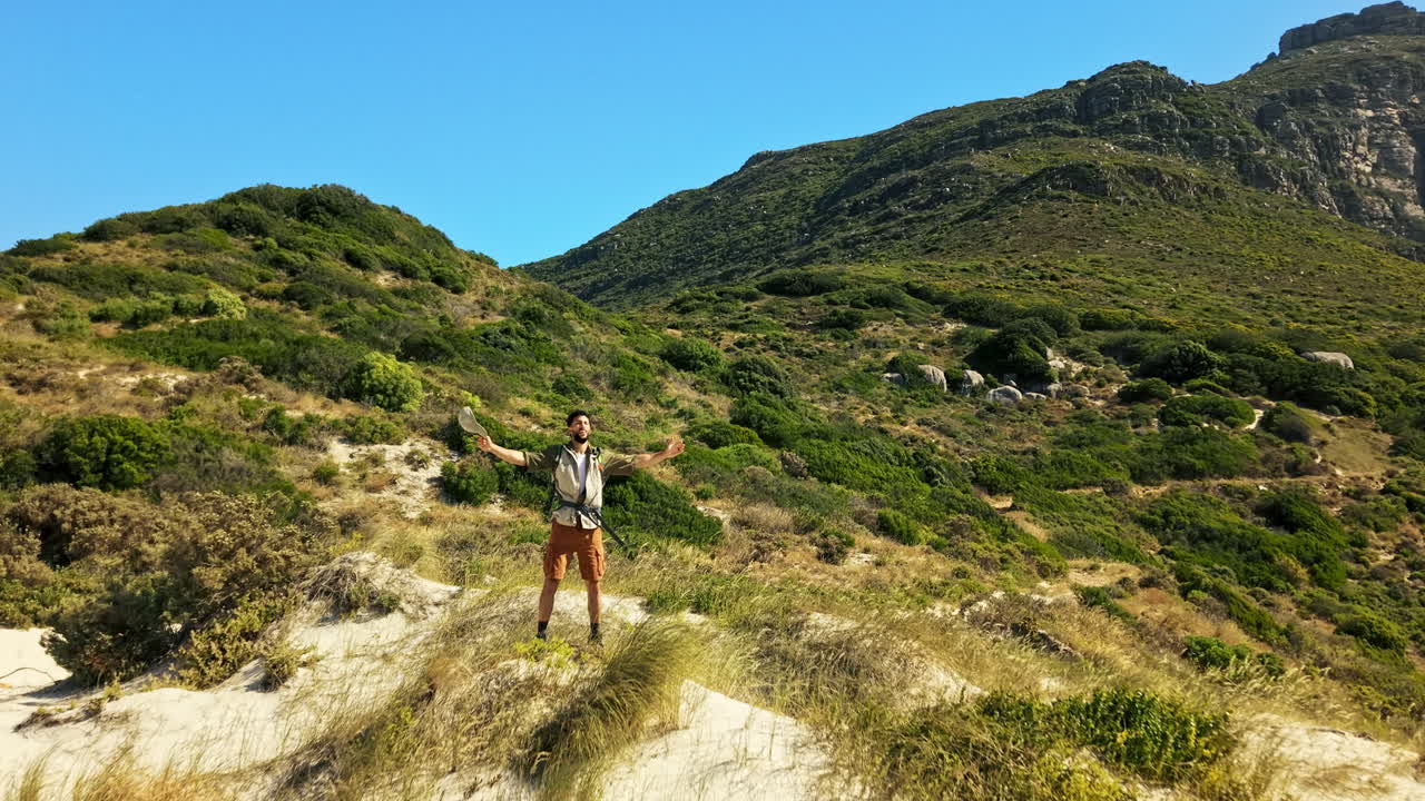 Uomo che celebra il successo su una duna di sabbia con montagne sullo sfondo