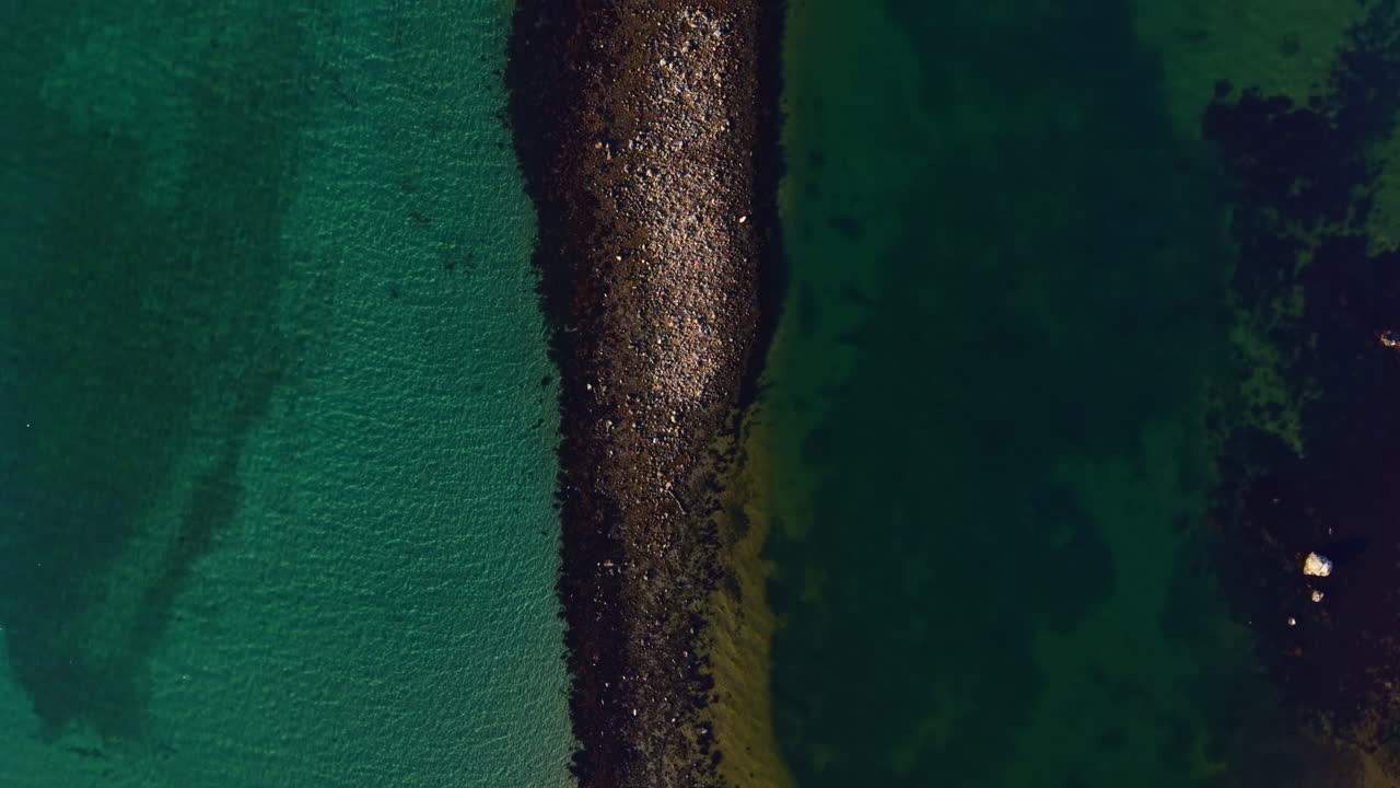 Et fengslende syn på kystlinjen som blander farger og teksturer ved strandlinjen under en rolig ettermiddag