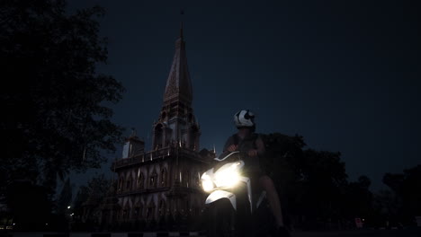 motorcyclist in front of a temple at night