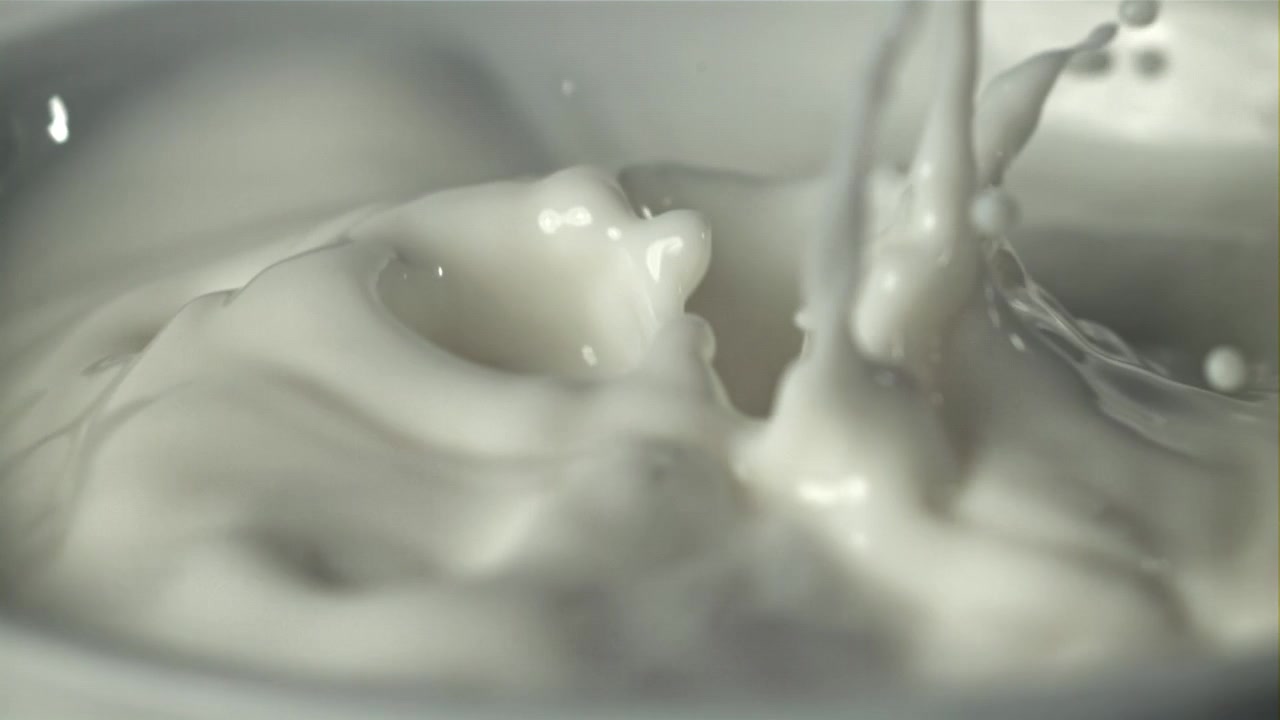 Nærbillede i slowmotion af sprøjtende mælk.