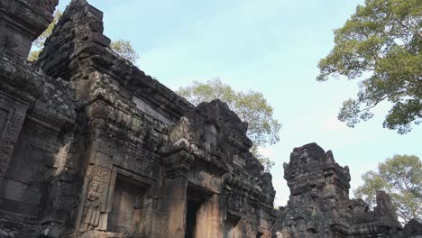 close exterior pan shot of historical temple ruins with trees in the daytime near angkor wat