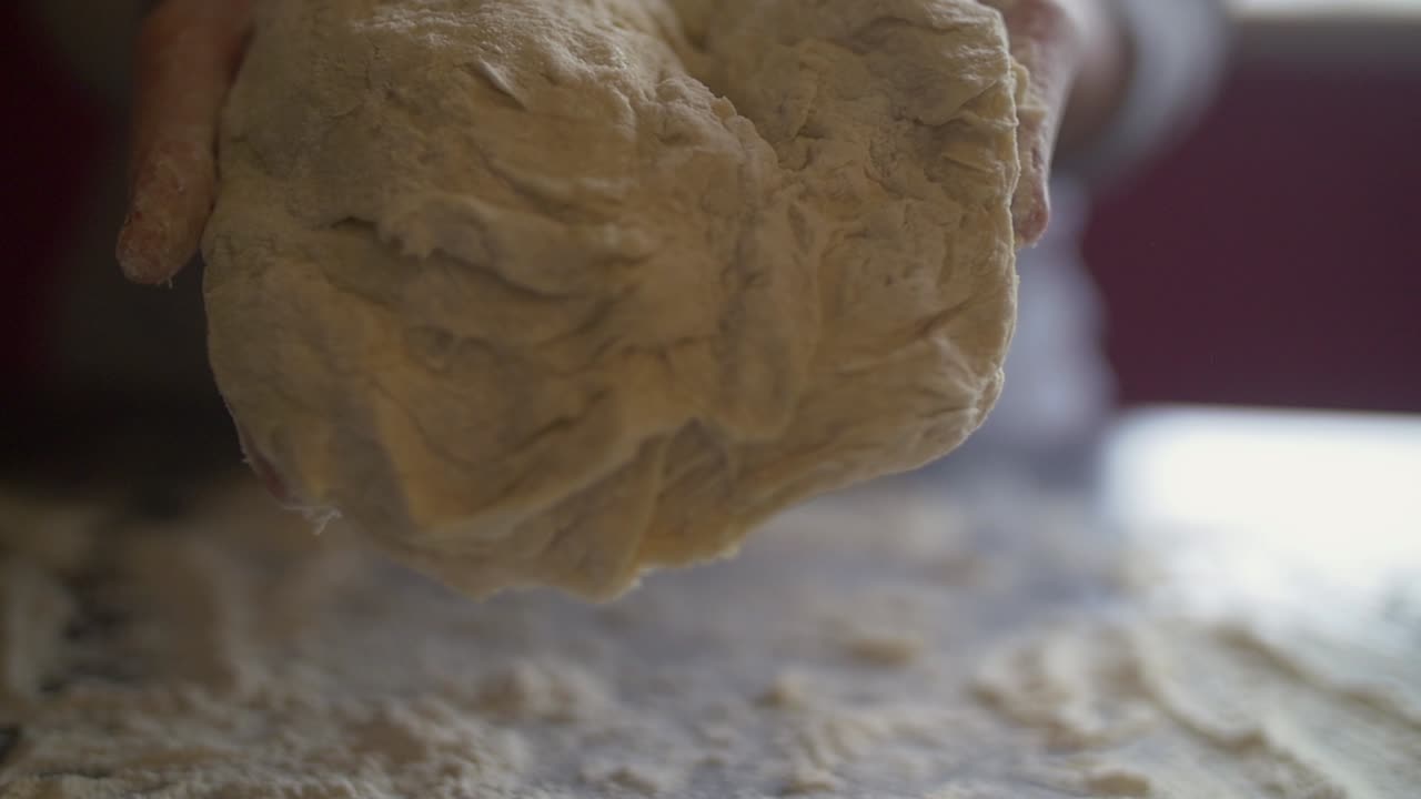 Woman's hand show to camera fully rounded ball of pizza dough