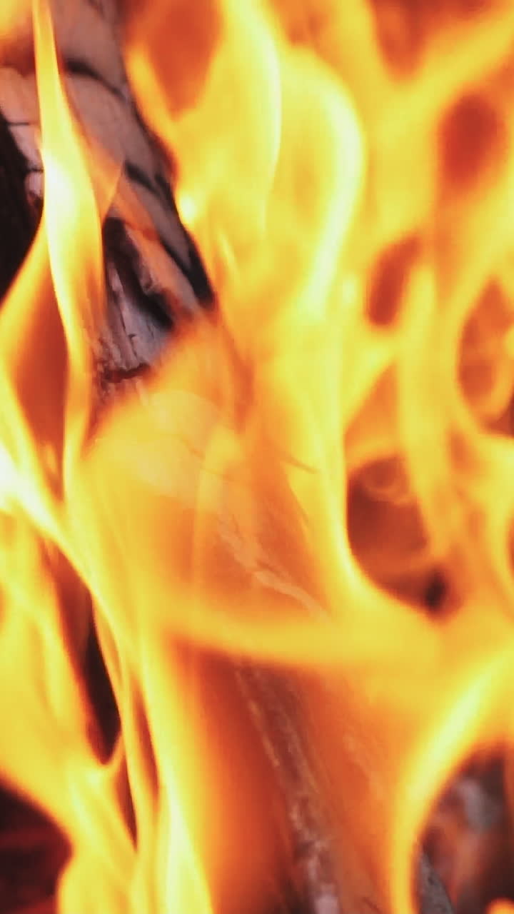 Burning wood in the fireplace and the flames. Bonfire. Slow motion Vertical video