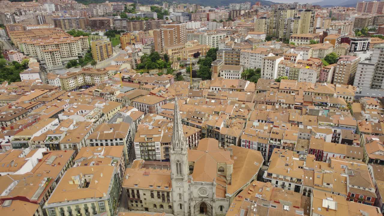 Aerial view of a European city with a prominent church spire and red-tiled roofs