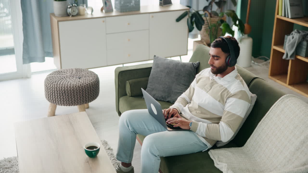 Man working on laptop with headphones at home