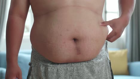 한 남자의 근접으로 그의 허리를 둘러싼 과도한 지방을 러