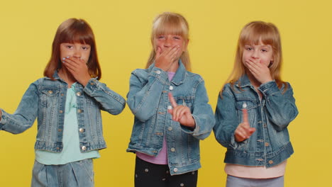 Three-cute-girls-siblings-friends-closing-mouth-with-hands-refusing-to-tell-terrible-secret,-truth