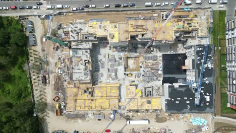 Aerial-top-down-view-on-the-rooftop-of-an-apartment-building-under-construction-with-tower-crane-and-a-lot-of-workers-laying-metal-rebar