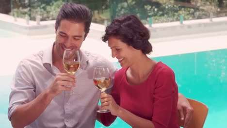 smiling couple drinking wine poolside