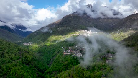 nubes que se forman sobre el pintoresco pueblo en la exuberante ladera del valle alpino italiano