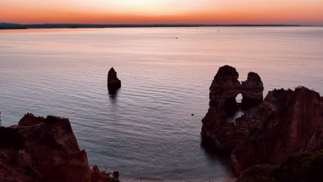 sunset over rocky coastline in portugal with tranquil water reflections
