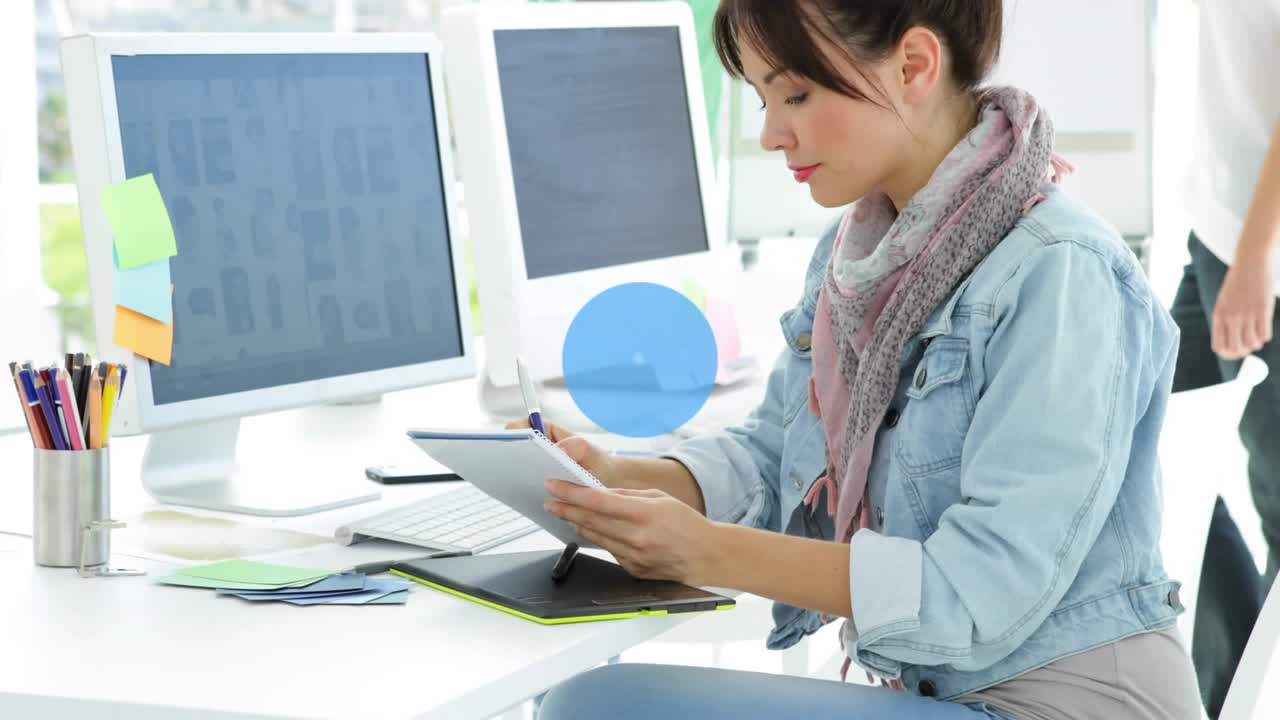 Seated woman using stylus, animating blue network linking monitors and team for design planning
