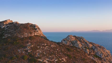 aerial: flying above rocky seashore at sunset time