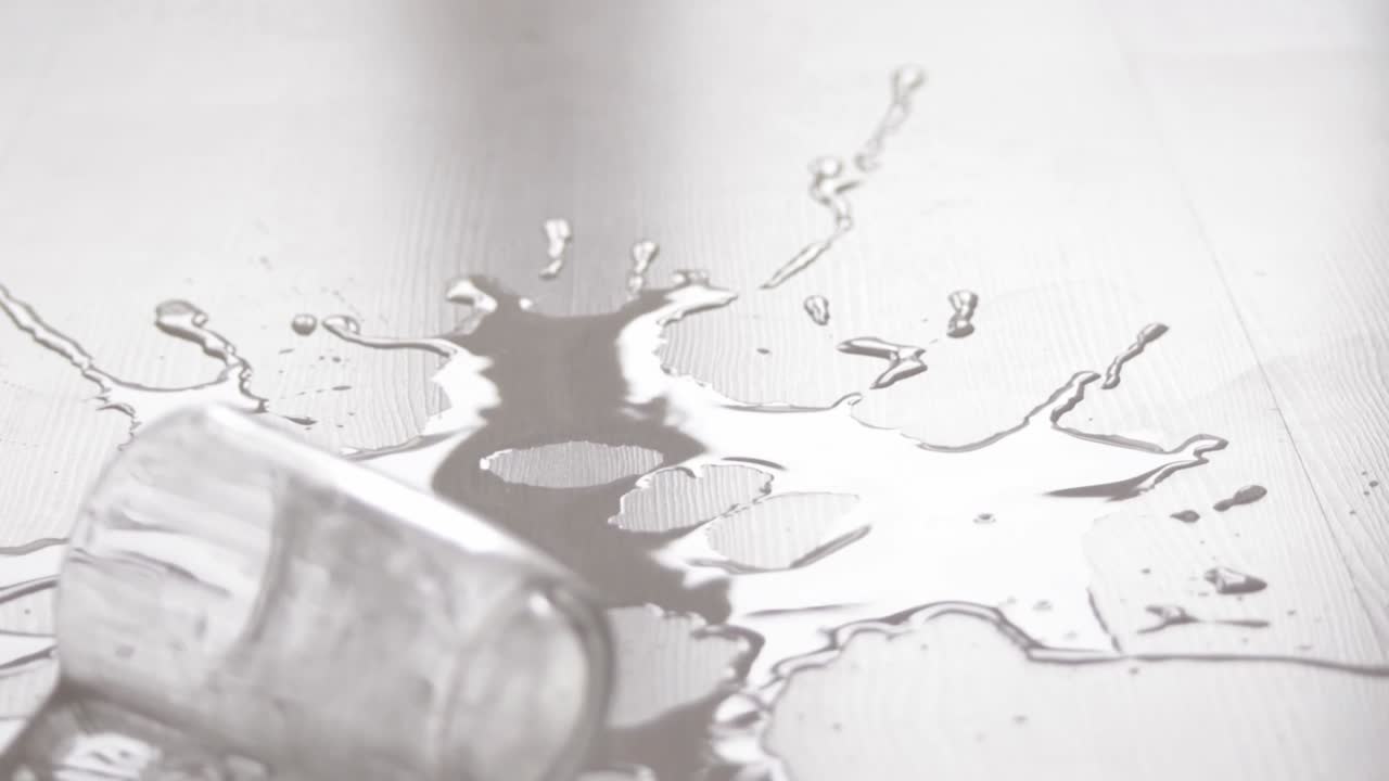 느린 동작으로 깨지지 않고 흰색 나무 바닥에 떨어지는 물 한 잔