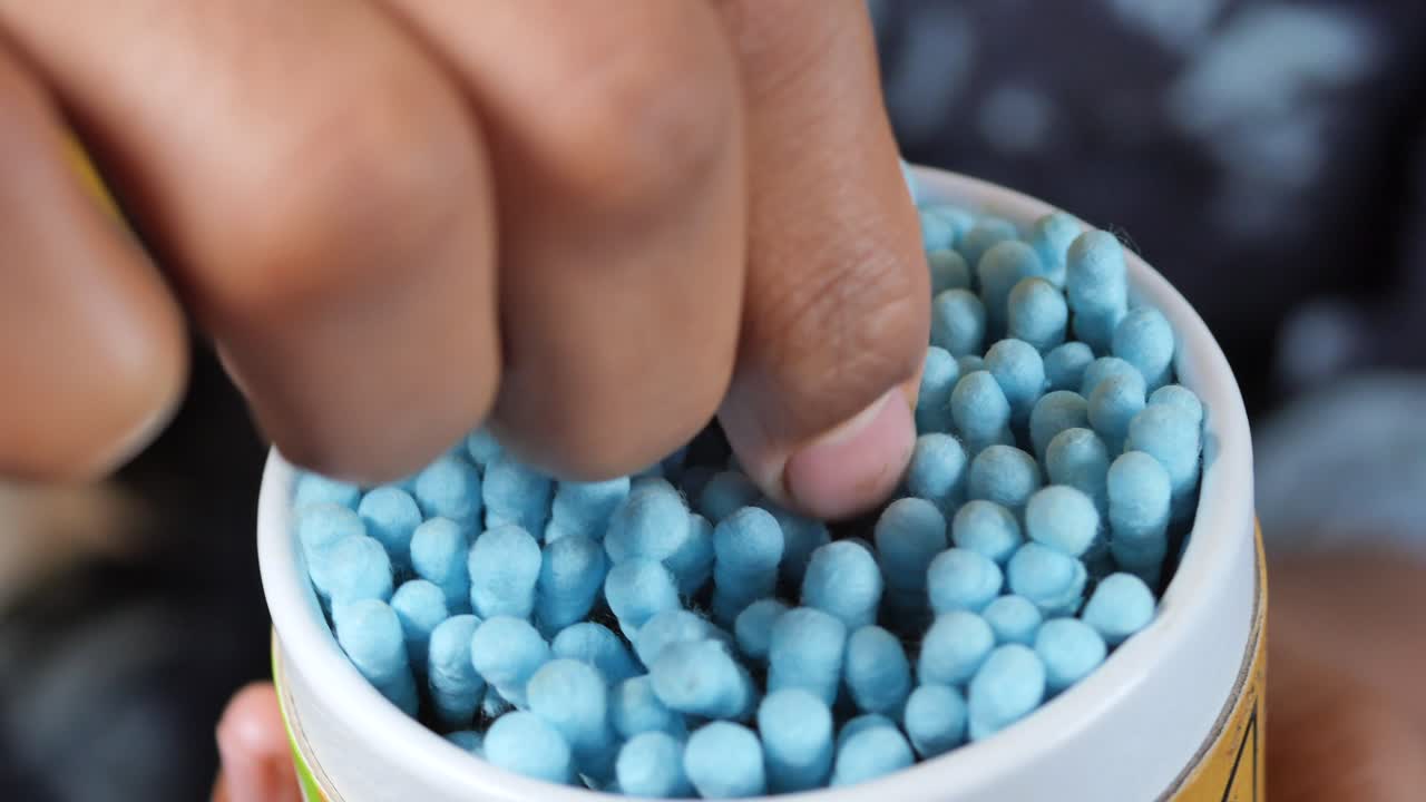 손으로 컨테이너에서 면화 스을 가져가는 것