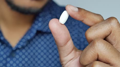 close-up of a person holding a white pill