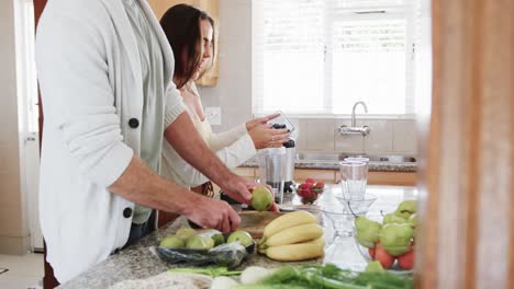 Feliz-Pareja-Caucásica-Preparando-Batidos-Saludables-En-La-Cocina,-Cámara-Lenta