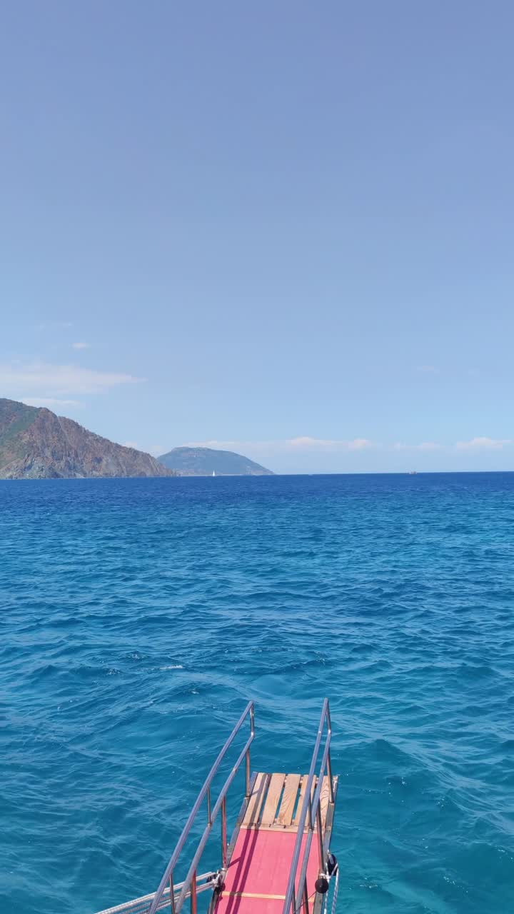 The ocean is calm and blue, with a few boats floating on the surface