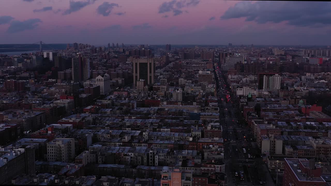 Gorgeous aerial footage of the Harlem neighborhood of New York City at sunset blue hour.  Traffic headlights, George Washington Bridge in the distance.  in 4K.