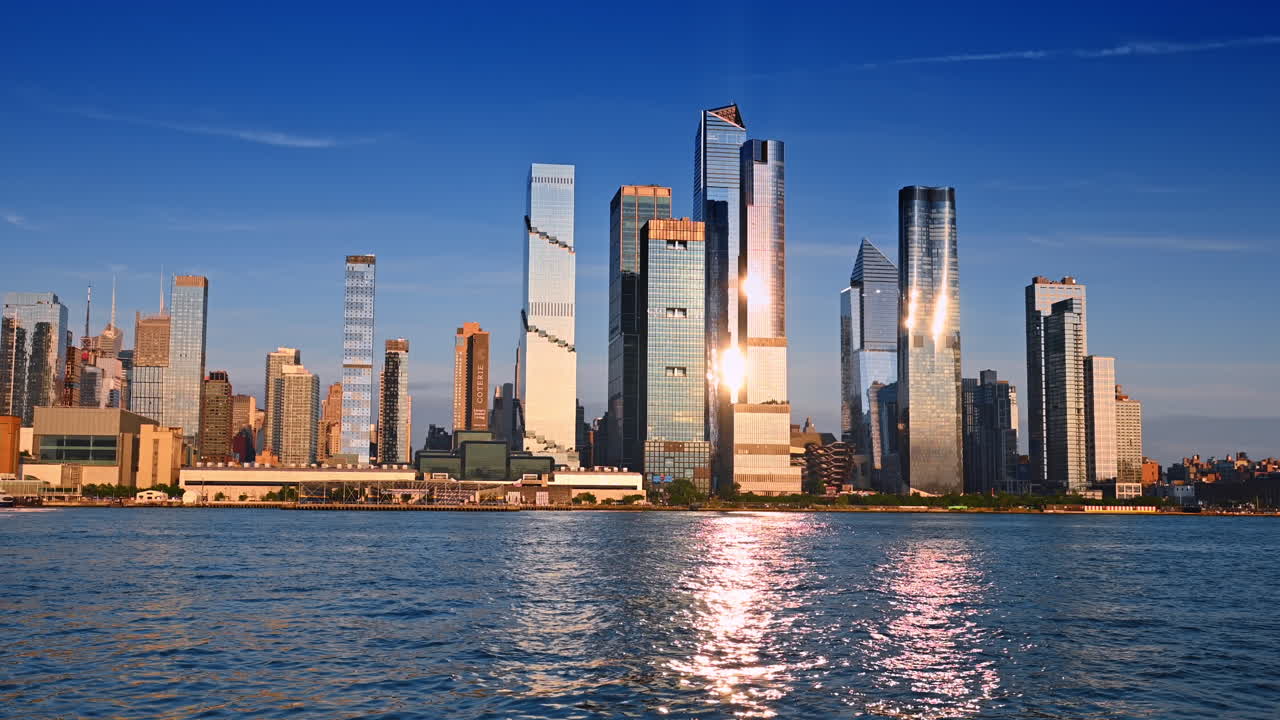 Vibrant skyline of New York at sunset. Glowing skyscrapers of New York reflect on water during a beautiful sunset, showcasing the city's vibrant architecture
