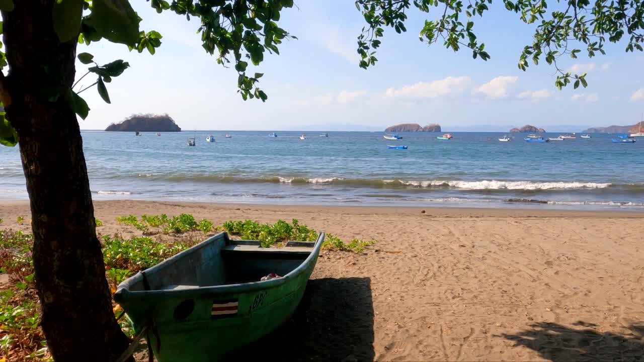 bote de madera en una playa tropical con un árbol en un día soleado, playa coco en guanacaste, costa rica