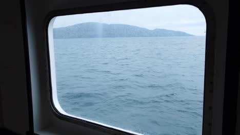 view looking out through passenger ferry window overlooking ocean towards isle of south uist in the outer hebrides of scotland