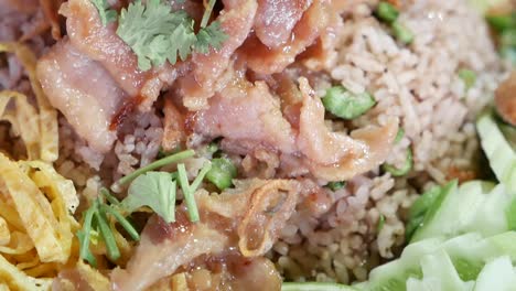 close up footage of thai style shrimp paste fried rice served with fried egg, sweet pork, deep fried chilli, sun dried shrimp, shallot, sliced long curd beans and mango