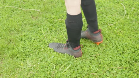 legs of soccer player standing on green grass, ready to come on pitch