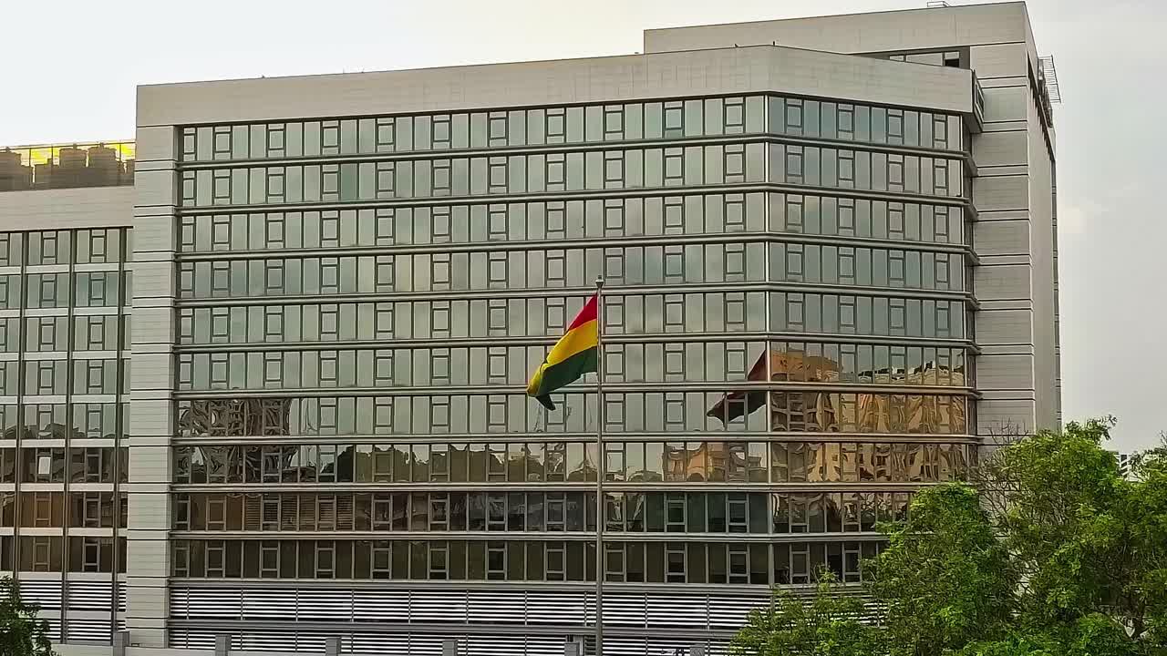 Construção com a bandeira de Gana em Accra refletida nas janelas durante a noite