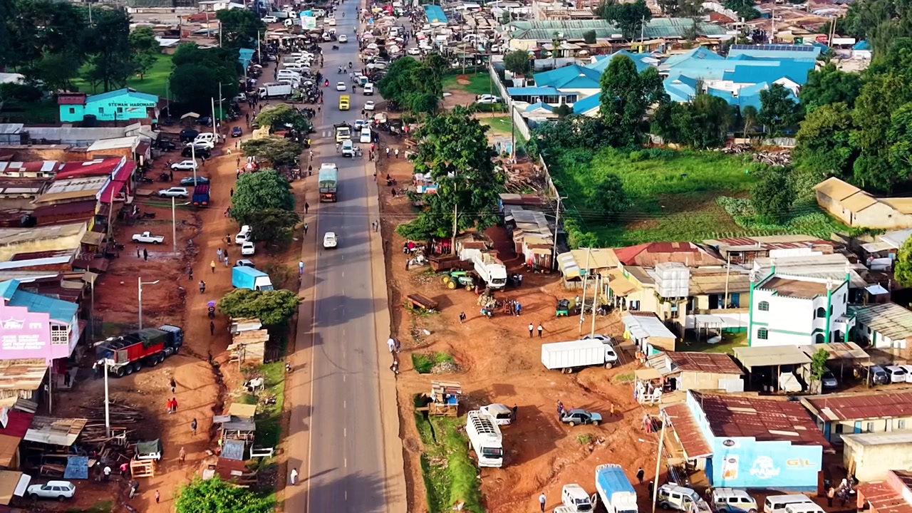 Strade del Kenya, strade rurali, insediamento rurale povero, strada danneggiata con drone che riprende veicoli sulla strada dall'alto