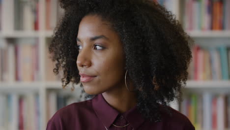 portrait young beautiful african american woman student looking pensive turns head black female with afro hairstyle slow motion bookshelf background