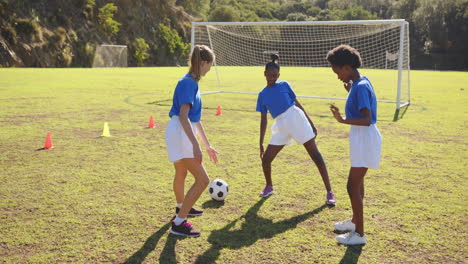 playing soccer on school field, girls in uniforms practicing with ball