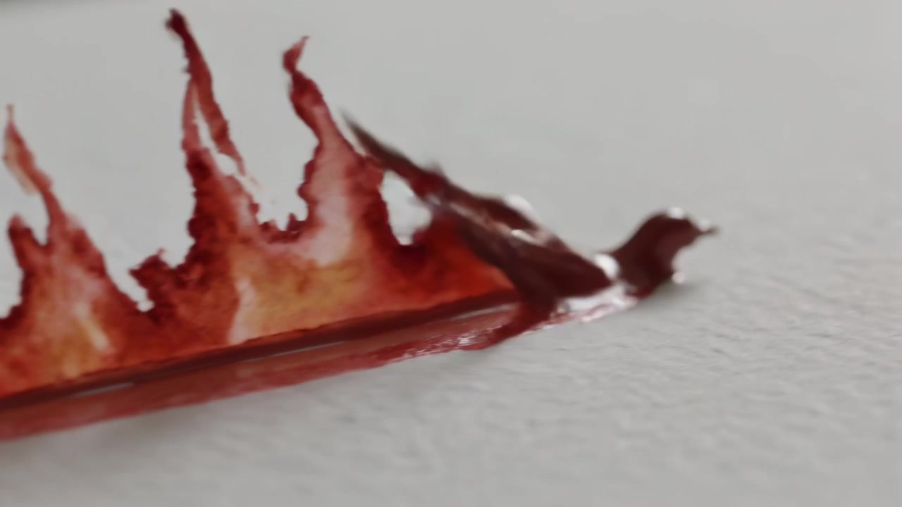 Un pennello tirato fuori dall'inquadratura trascina acquerello rosso su carta ruvida, creando un colore stratificato.