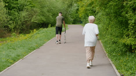 man with walking aid and woman walking in park