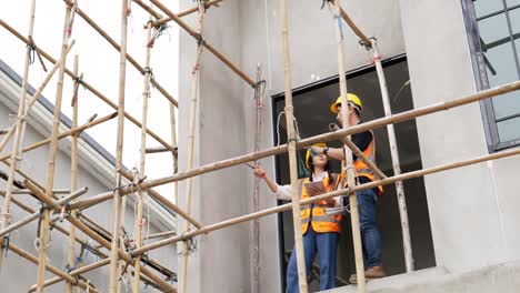 4k low angle view . a young male and female asian civil engineers holding a tablet and working together at balcony .