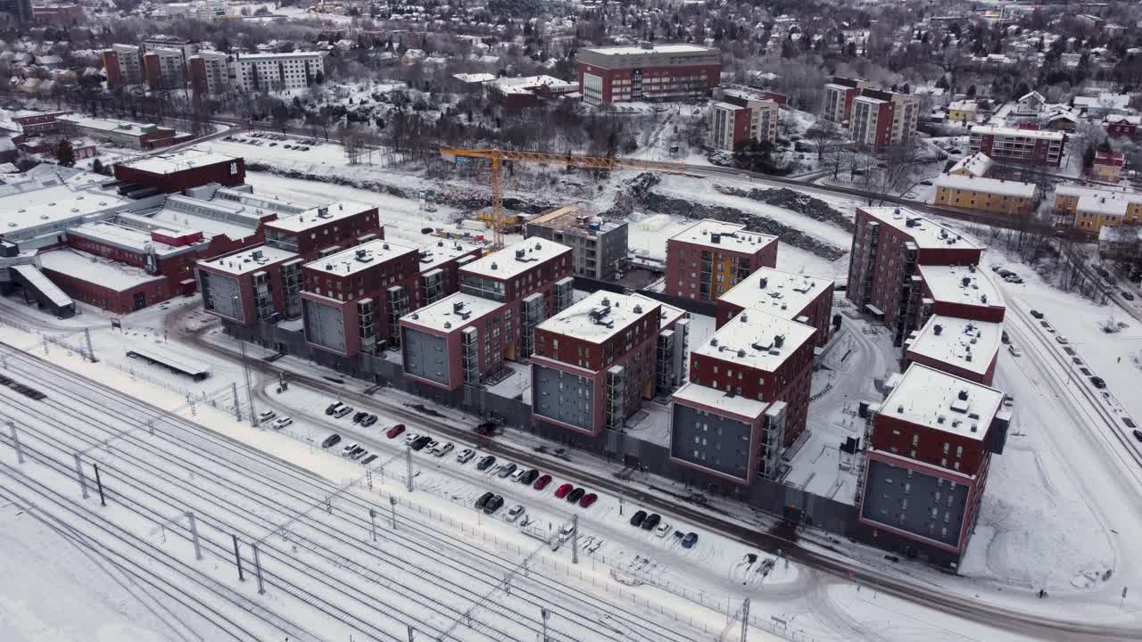 современные жилые дома рядом с железнодорожными путями в снежный зимний день