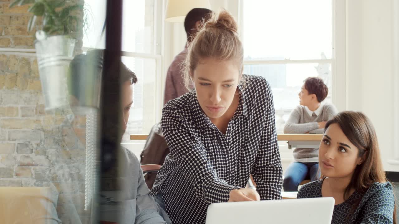 A group of diverse businesspeople talking and brainstorming during a meeting using a laptop. Young businesswoman talking to staff team collaborating with colleagues. Coworkers in a business meeting