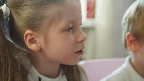 little girl talks to toddler boy sitting nearby in room