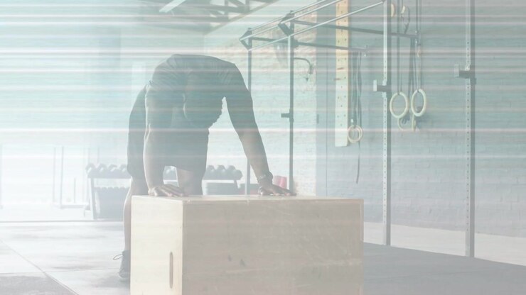 Man bracing plyo box, shifting weight, stepping up, driving upward for fitness amid lens flare