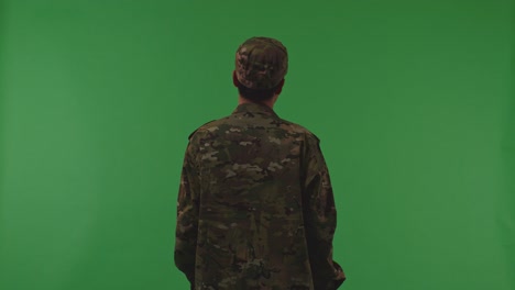 back view of distressed asian male soldier shaking his head being sad due to the war while standing on the green screen background