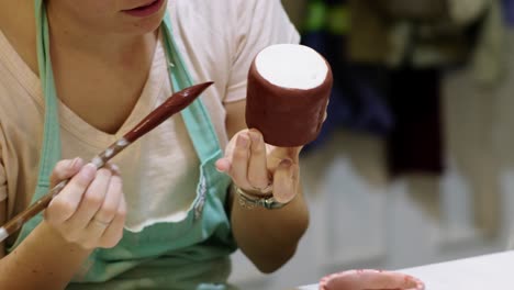 Primer-Plano-De-Una-Mujer-Pintando-Piezas-De-Cerámica-Con-Un-Pincel-En-Un-Taller-Durante-El-Día